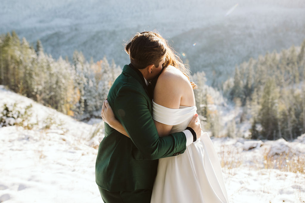 two brides hug in front of snowy mountains during olympic national park elopement