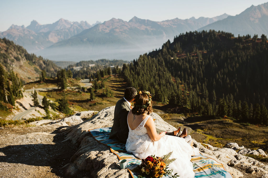 bride and groom sit on edge of cliff during north cascades elopement