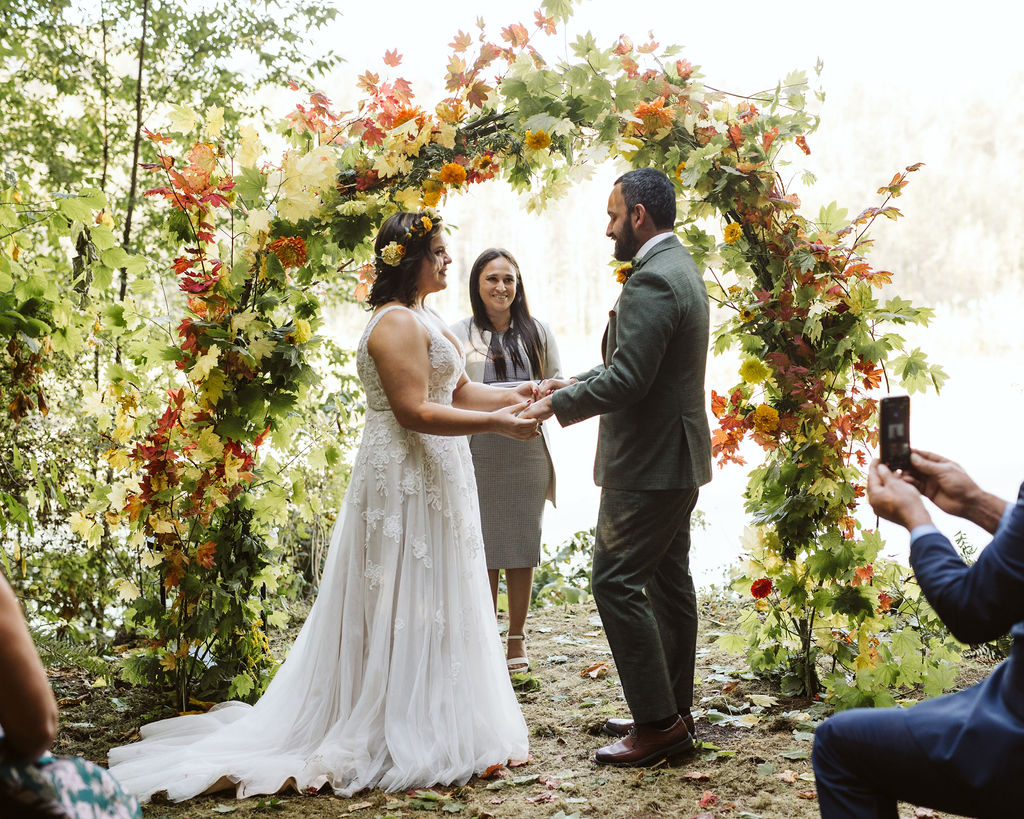 bride and groom stand in front of floral arch during airbnb intimate wedding