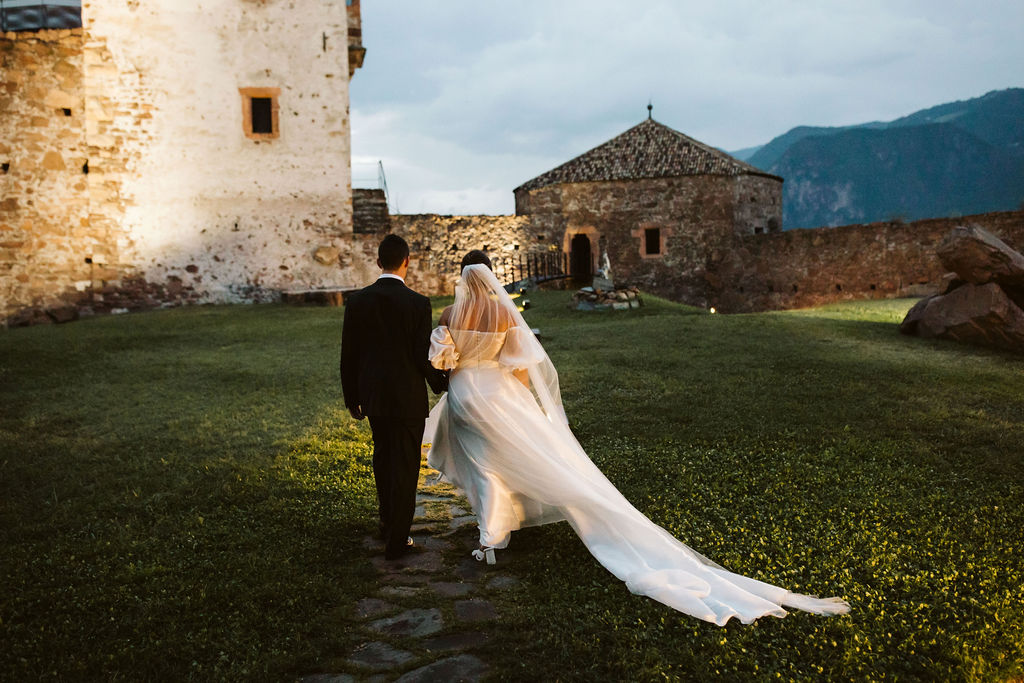 bride and groom walk at twilight up a bath towards a castle