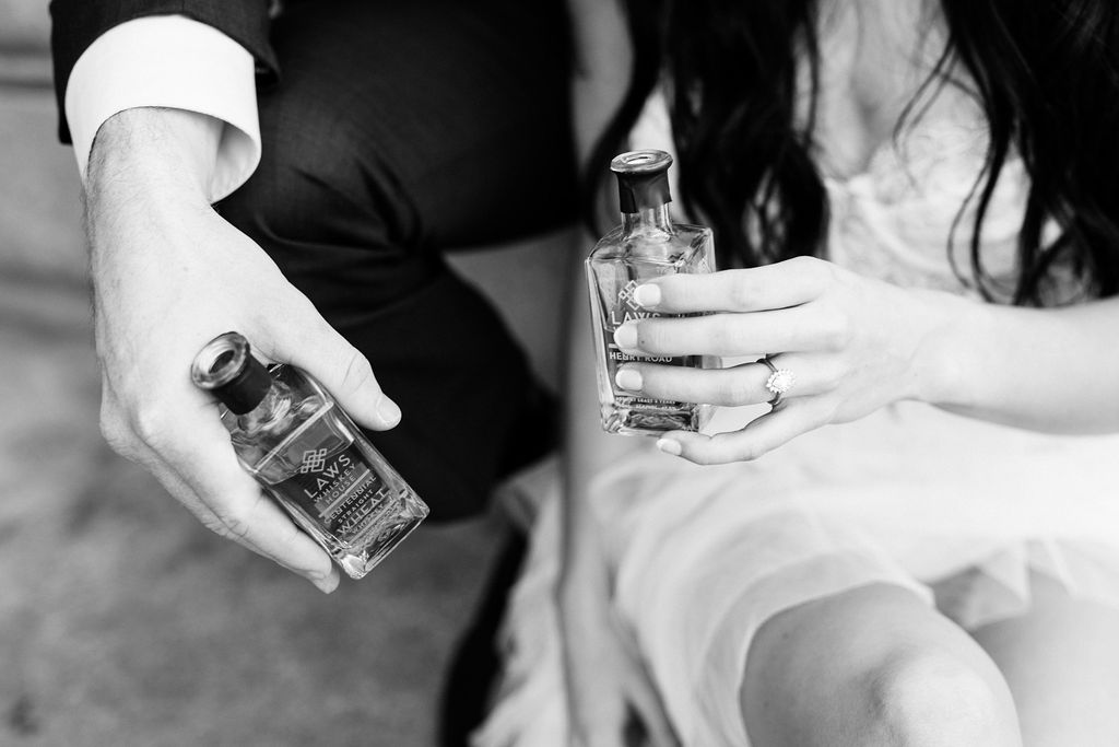 bride and groom hold small bottles of alcohol