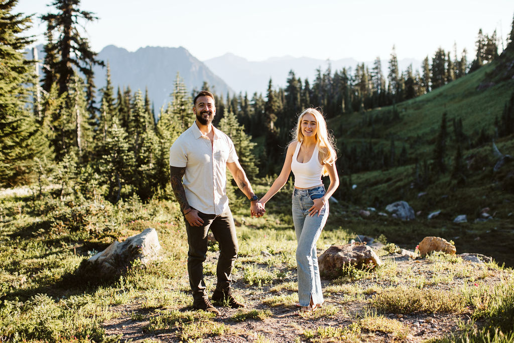 boy and girl stand next to each other holding hands at mt rainier engagement session