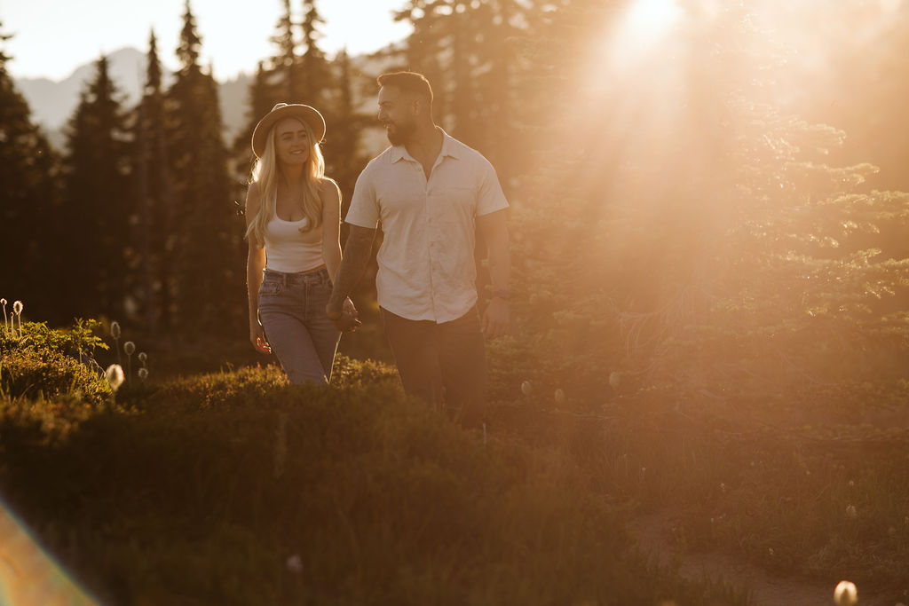 boy and girl walk in the sunlight together holding hands at mt rainier engagement session