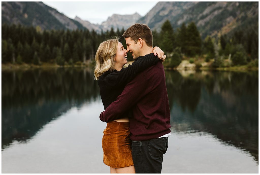 couple hugging mountains reflecting in lake fall engagement shoot outfit