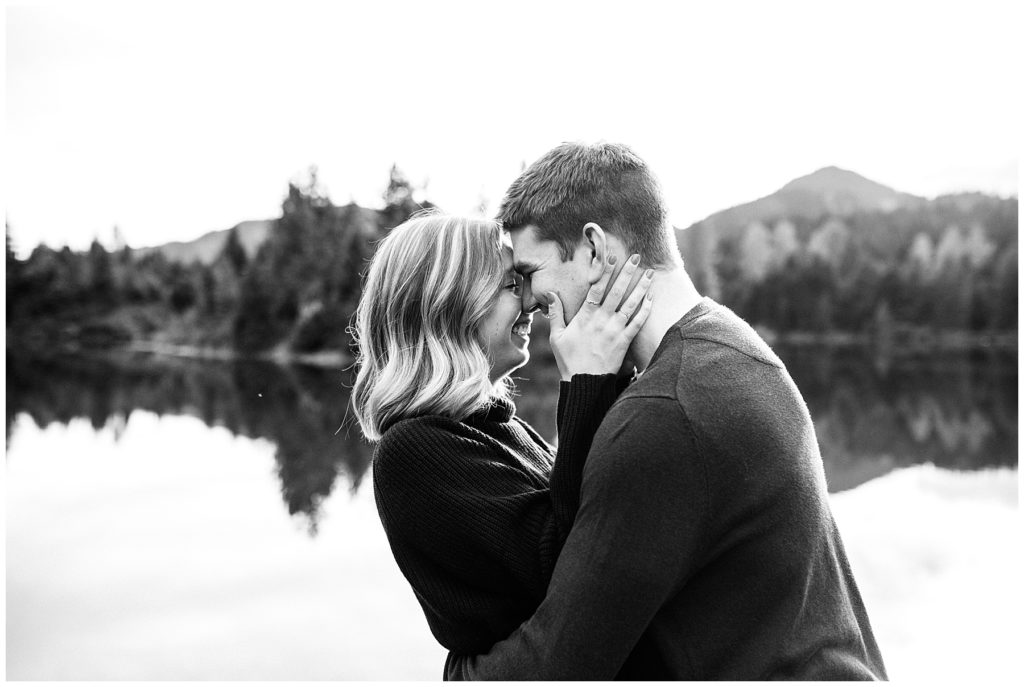 couple kissing black and white photo fall background trees and lake