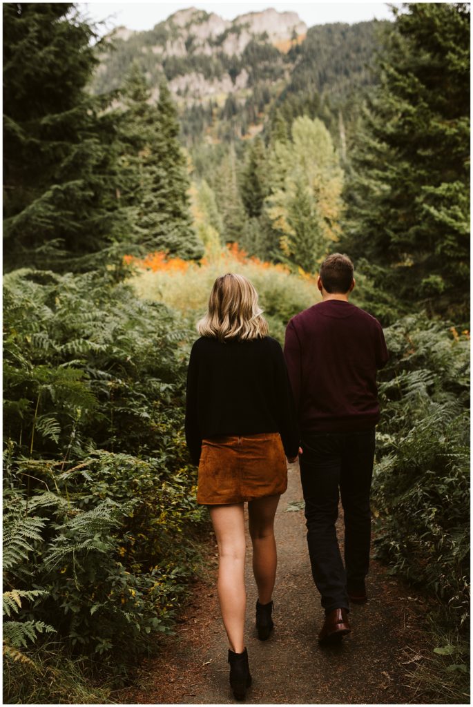 couple walking into forest mountains in the background forest greenery 