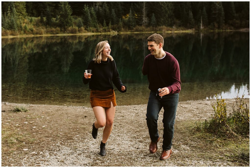 couple laughing with drinks and lake in background