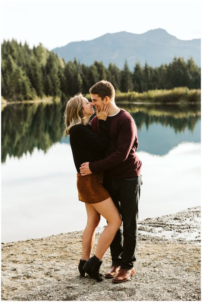 couple kissing by lake fall engagement outfits ankle boots maroon sweater