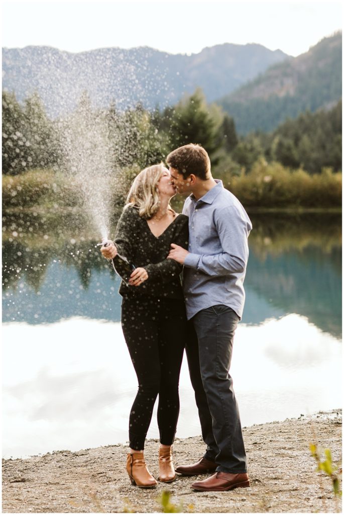 couple kissing fall engagement shoot outfits lake in the background