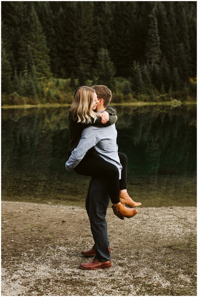 couple hugging lake and forest in background