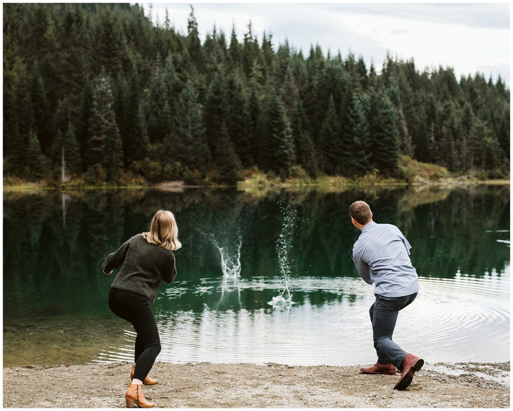 couple having fun throwing rocks in lake 