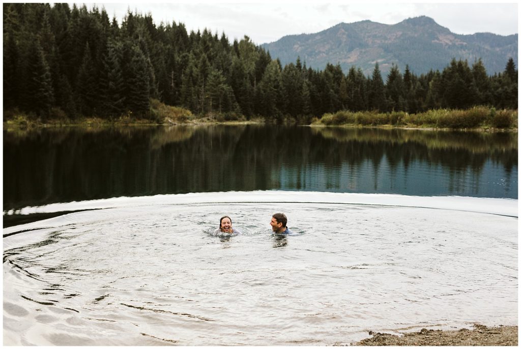 couple laughing in lake with clothes on