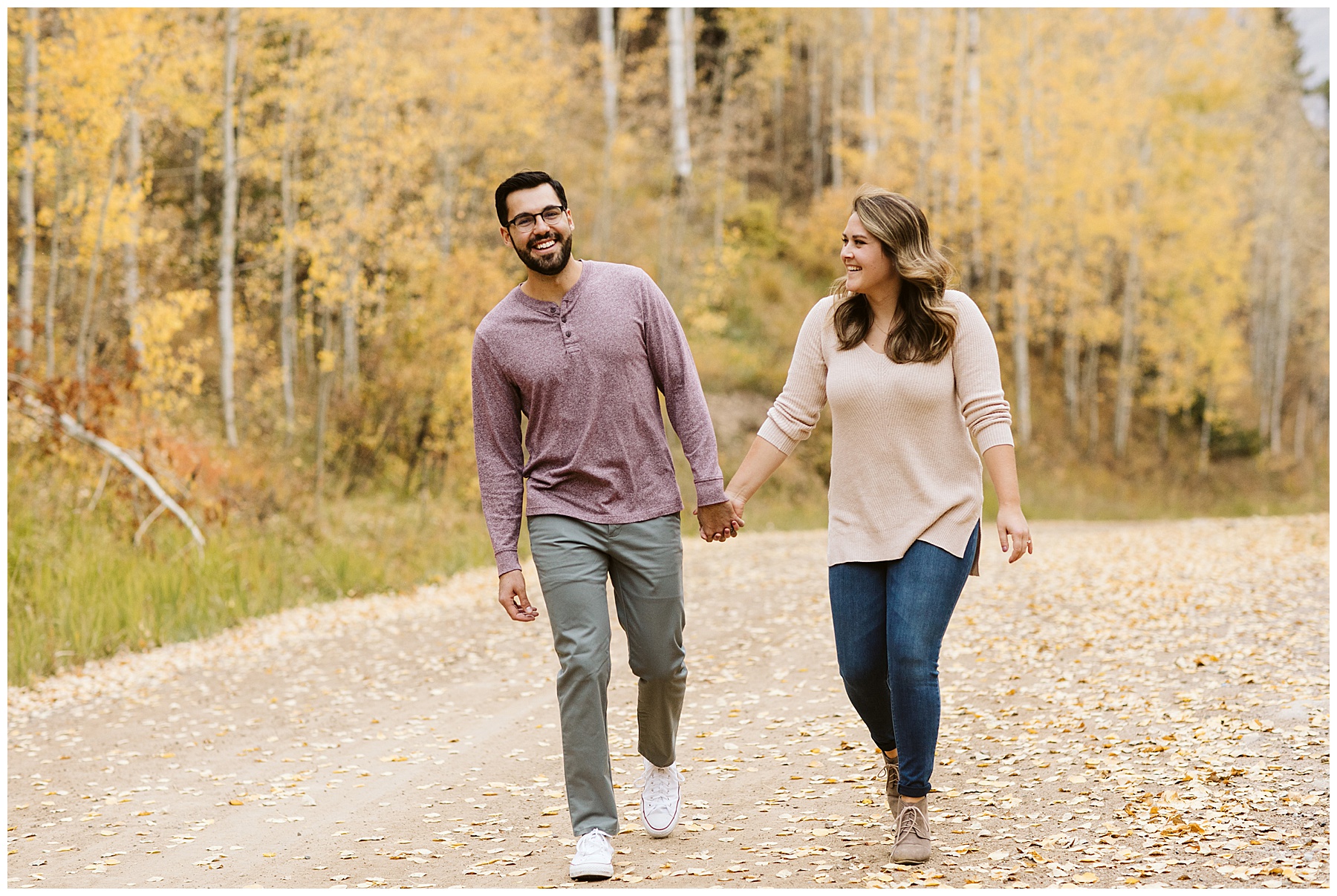 couple walking on road holding hands at their fall engagement photos session