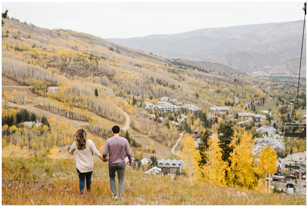 couple walking away toward mountains and aspen trees