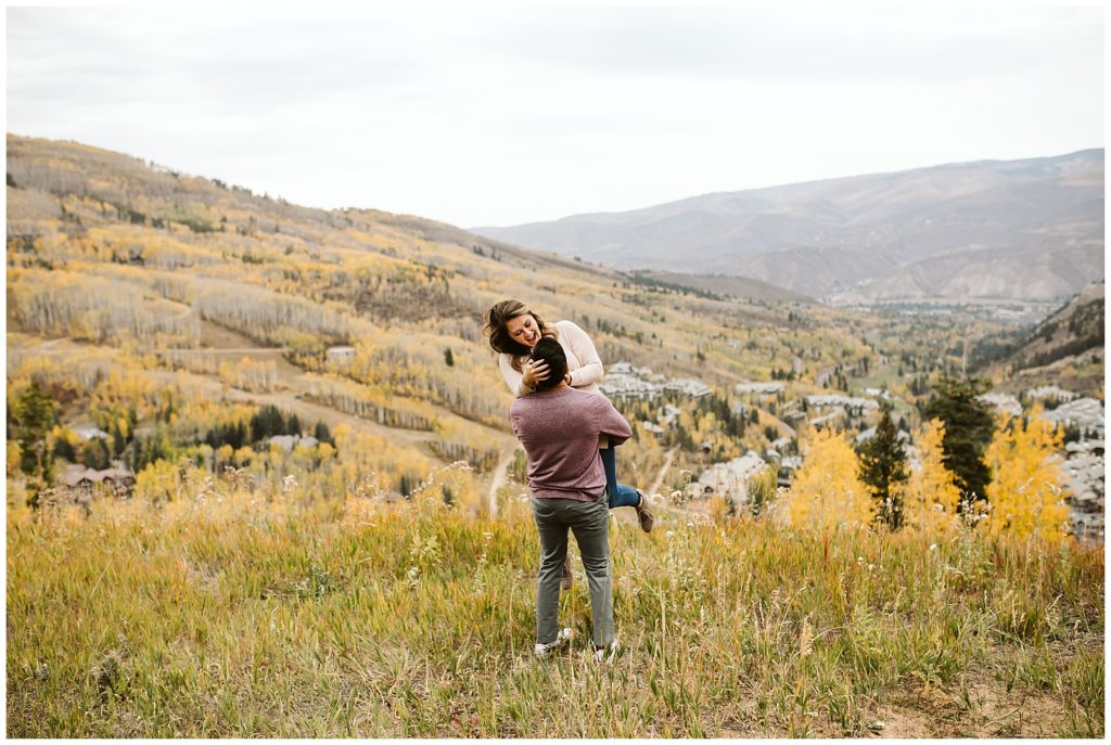 man picking up woman in landscape photo with fall aspen forest in the background yellow colors