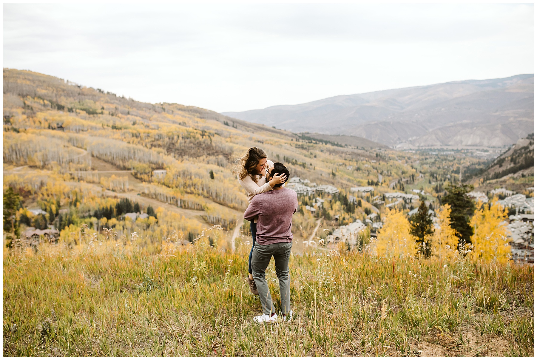 landscape photo with couple hugging and aspen forest and town in the background; the Colorado Aspens in the perfect spot for engagement photos in the fall.