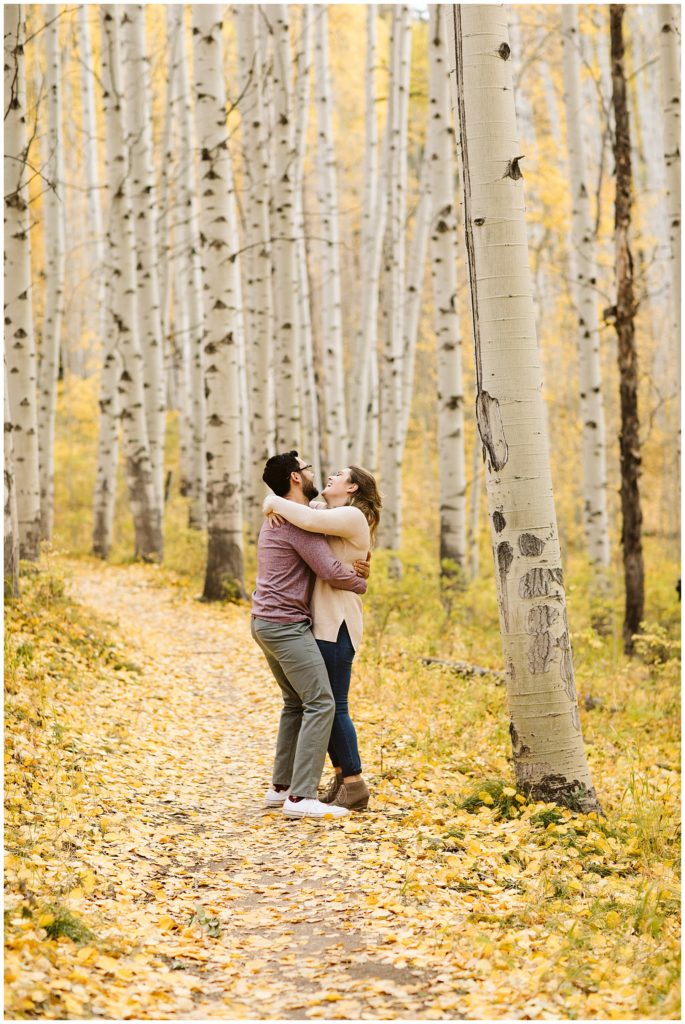 couple laughing and hugging in aspen forest fall colors