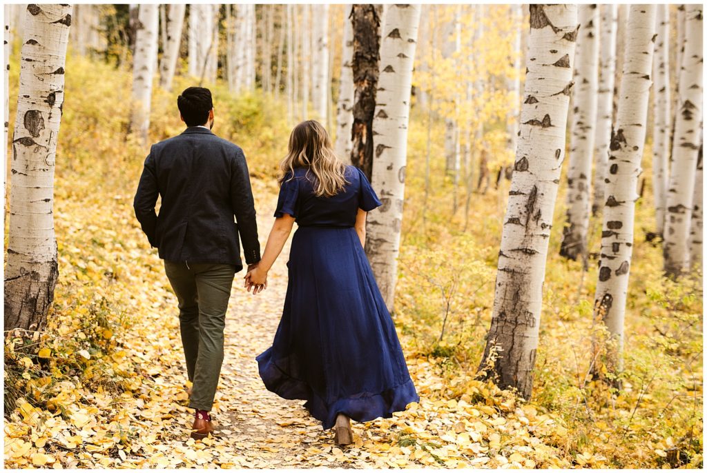 couple walking through aspen forest with blue dress