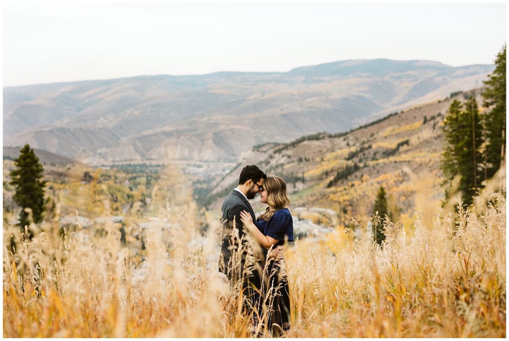 couple standing in brown grass with mountains in the back