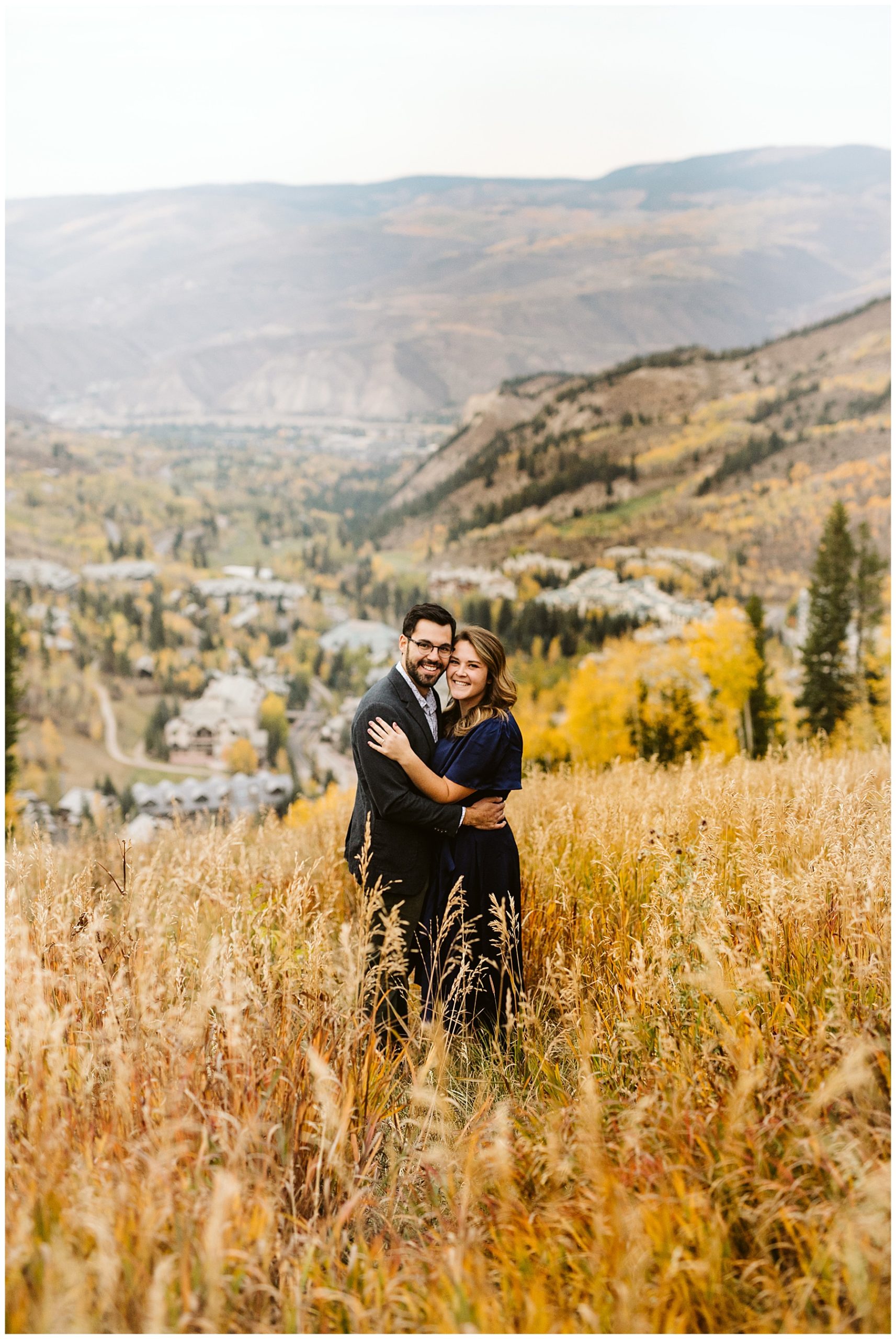 couple hugging with yellow fall trees and mountains in background