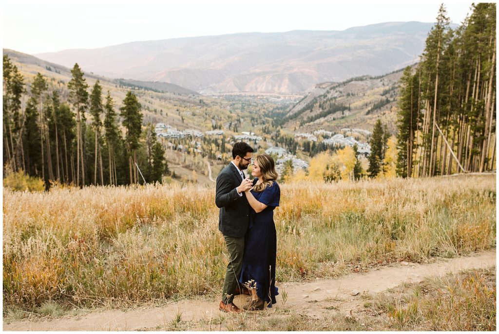 couple dancing in grassy field fall colors and trees