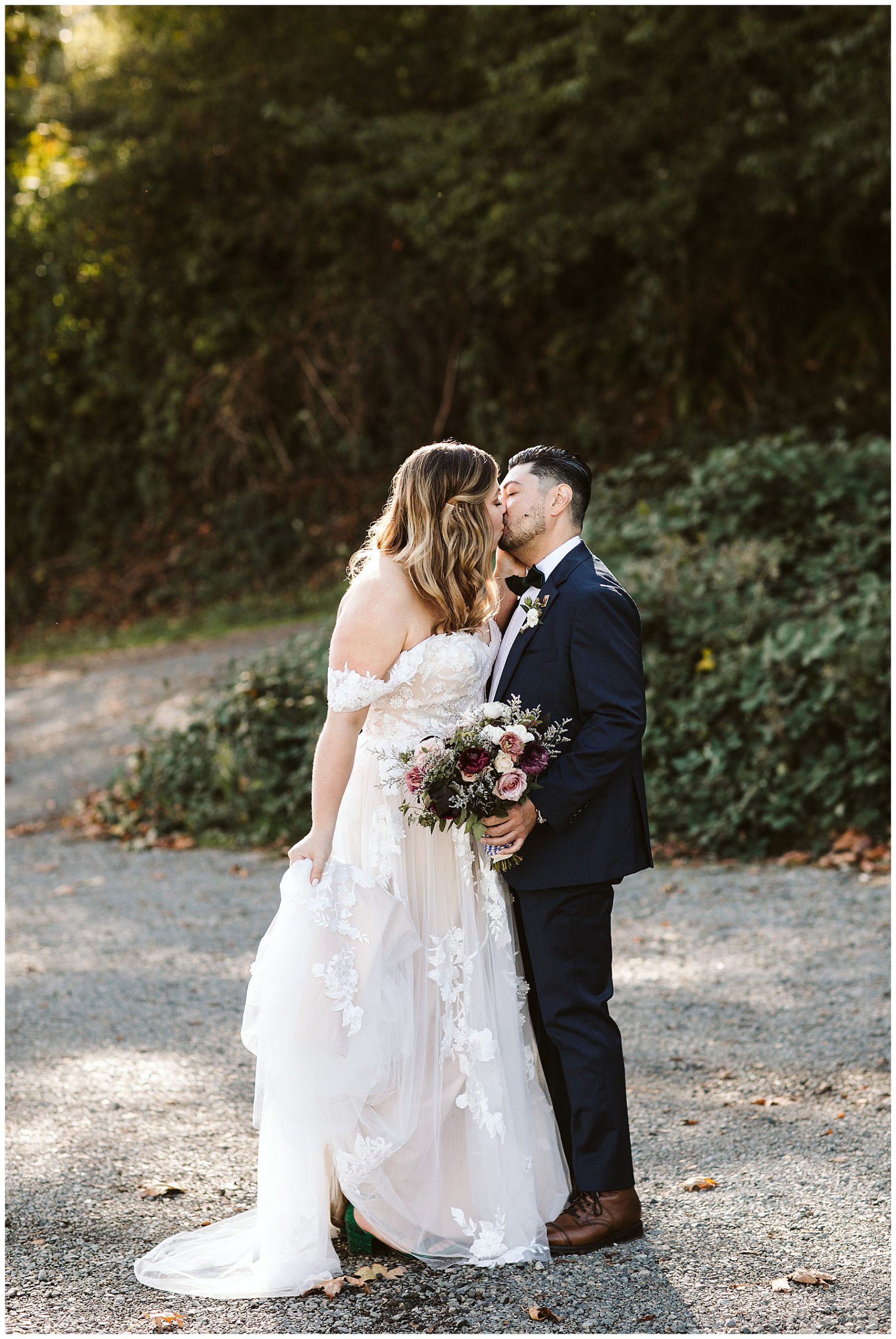 bride and groom kissing while holding purple bridal bouquet on Vashon Island in Washington