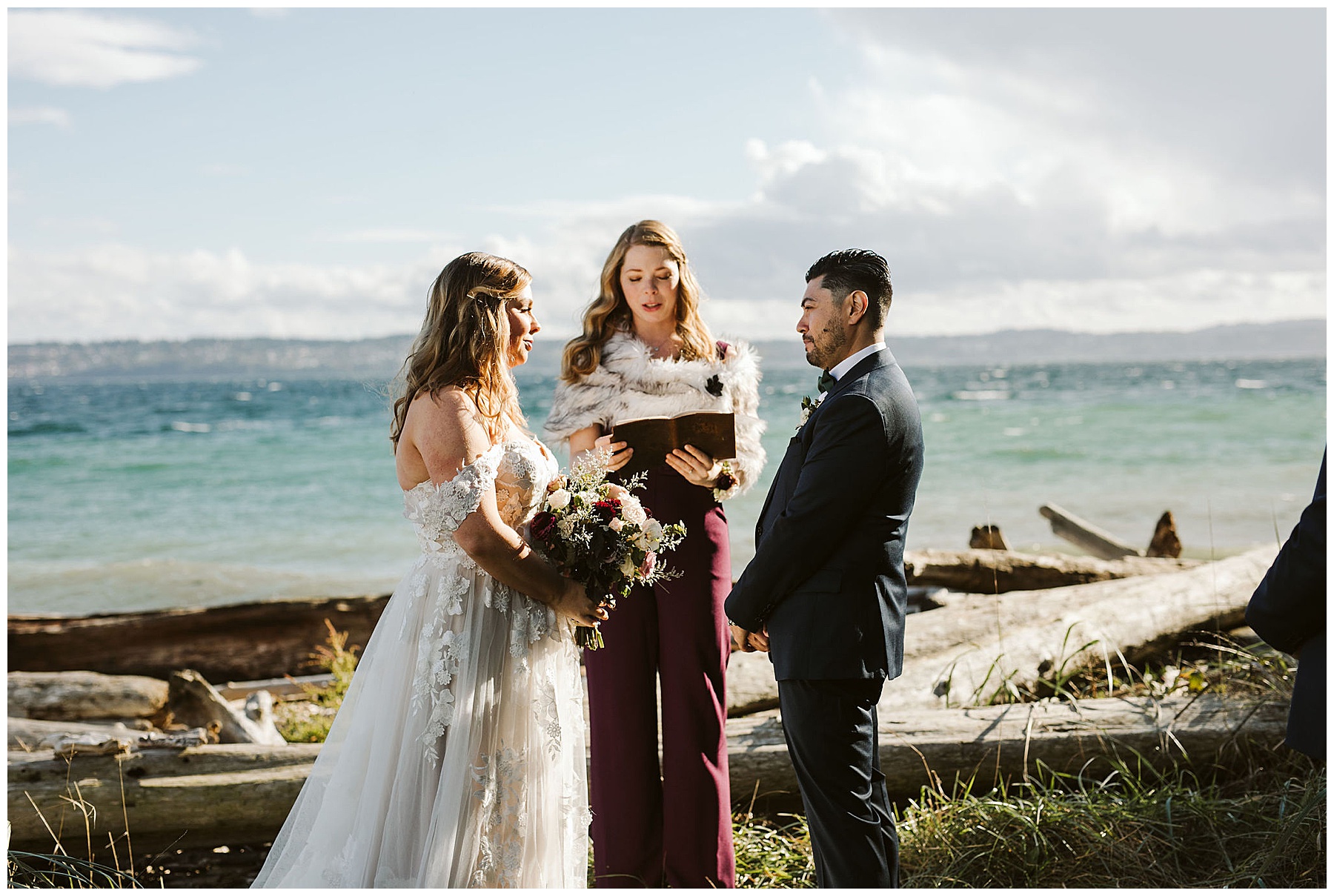 bride and groom standing by the water on Vashon Island in Washington, being read their vows