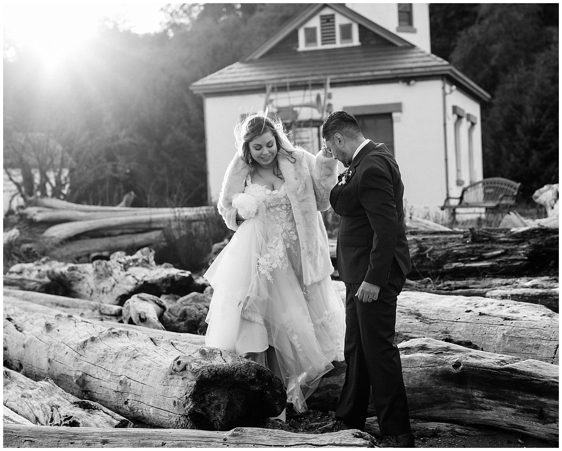 bride and groom walking on beach with driftwood black an white photo