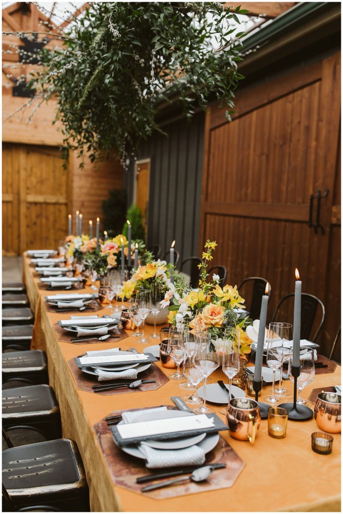 large dinner setting with bright orange table cloth and yellow and orange flowers