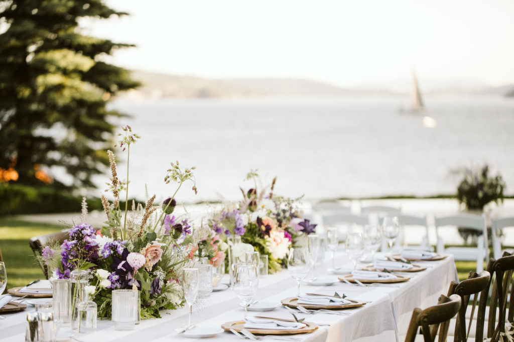 beautiful table setting with flowers as centerpieces near water