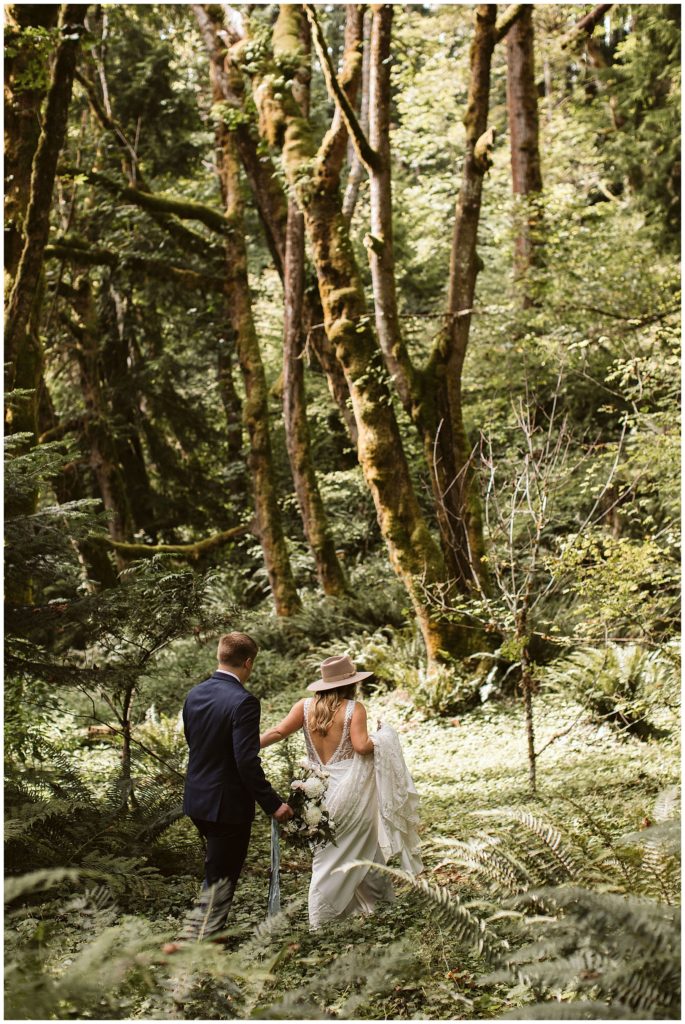 boho wedding couple walking into the forest
