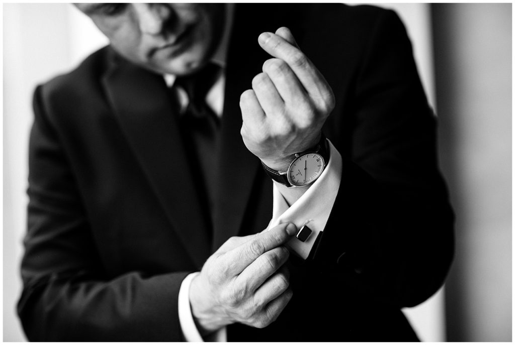 black and white photo of groom adjusting cuff links