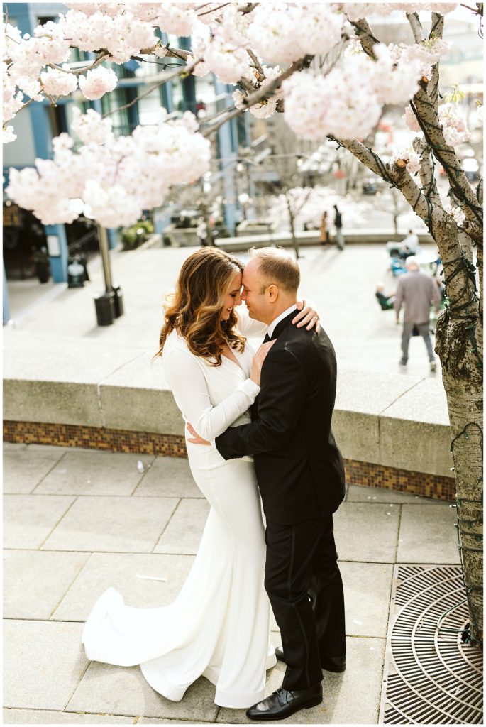 bride and groom touching foreheads with cherry blossoms framing the picture