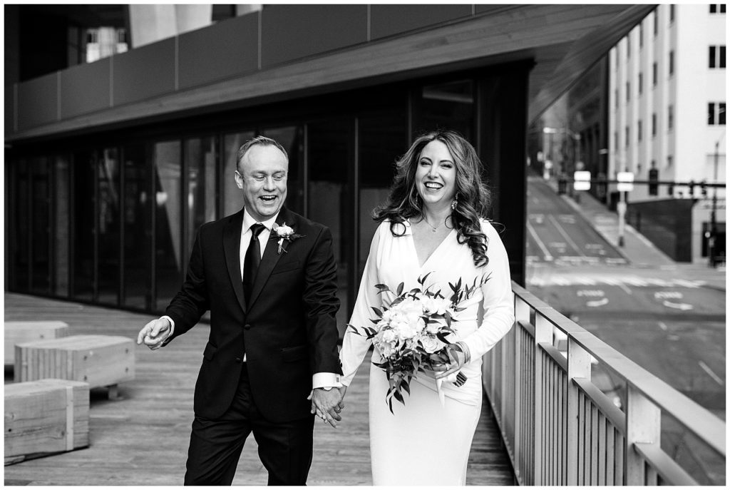 black and white photo of bride and groom laughing walking 