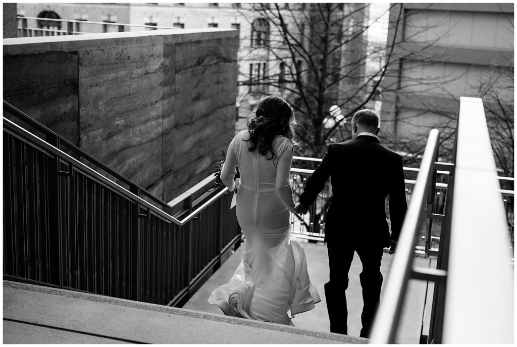 black and white photo of couple walking down stairs from the back