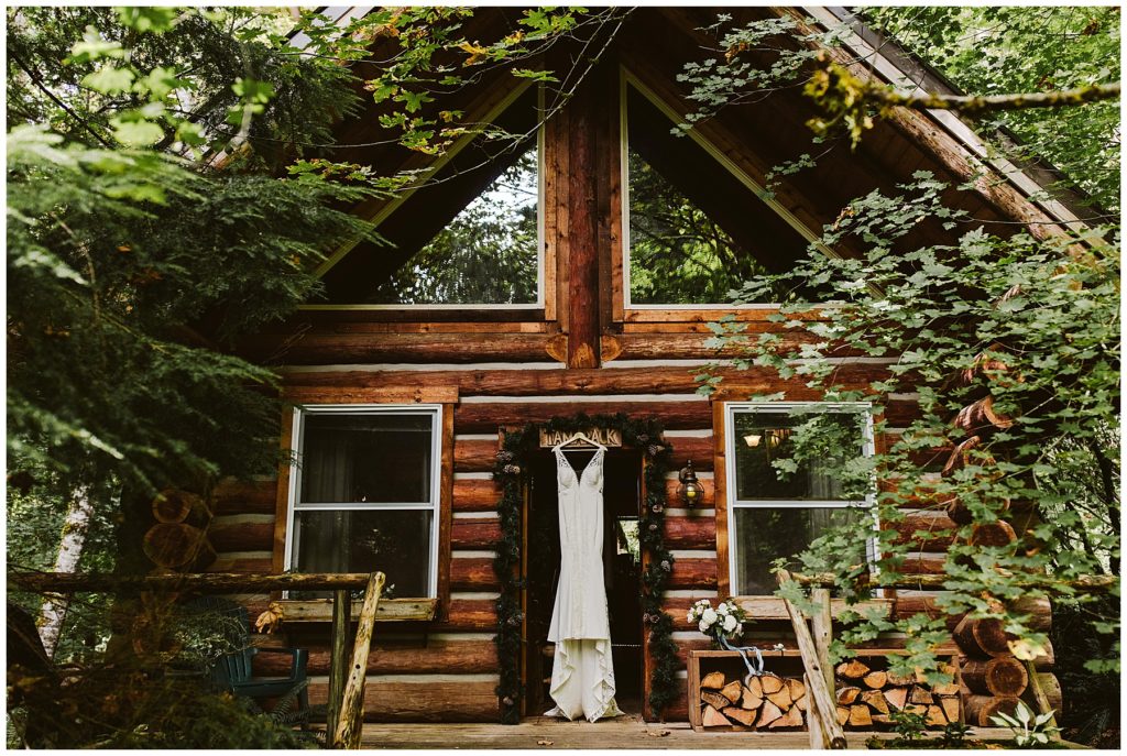 white wedding dress hanging from the door frame of a wood cabin