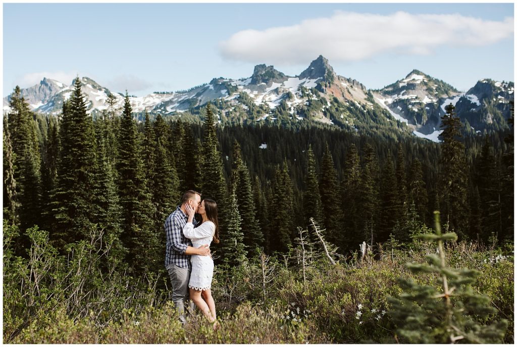 beautiful couple kissing with mount rainier in the background and a dark green forest
