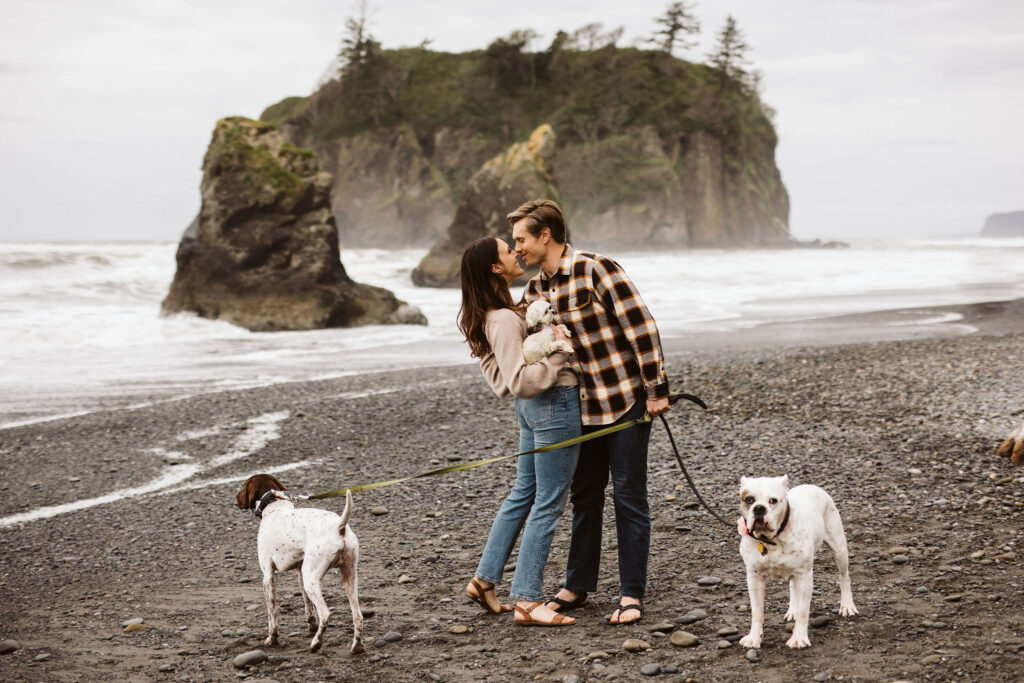 boy and girl pose with their dogs on the beach during olympic elopement
