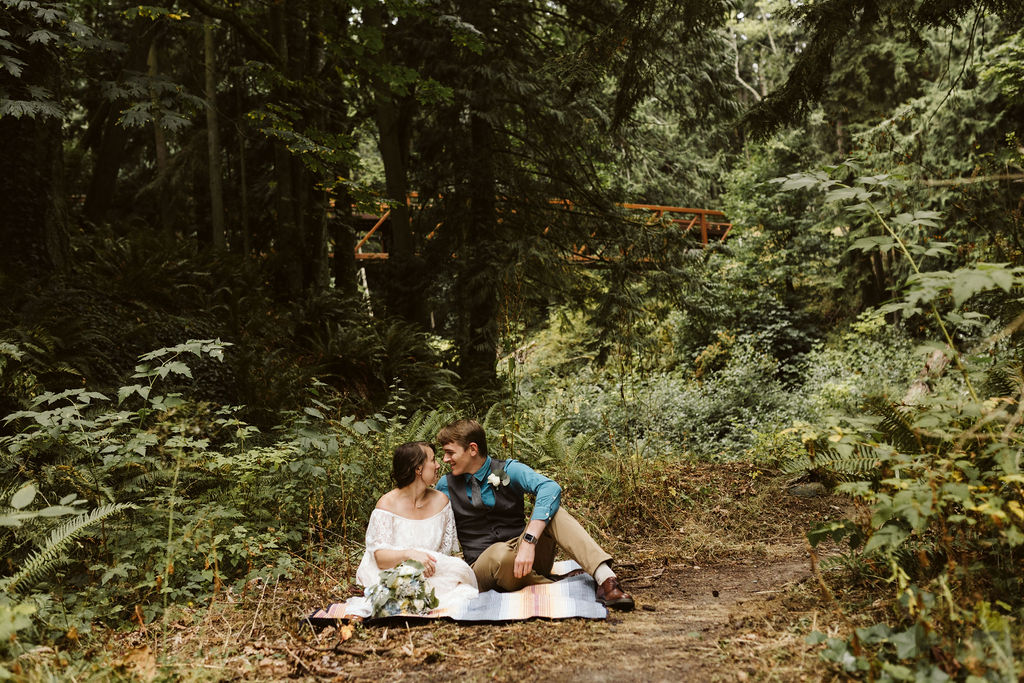 bride and groom sit in the forest during olympic elopement