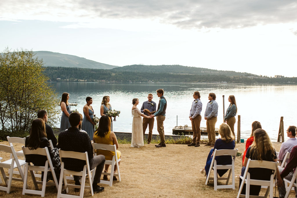bride and groom stand in front of lake during intimate wedding