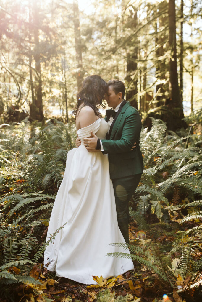 two brides stand with foreheads against each other during olympic national park elopement