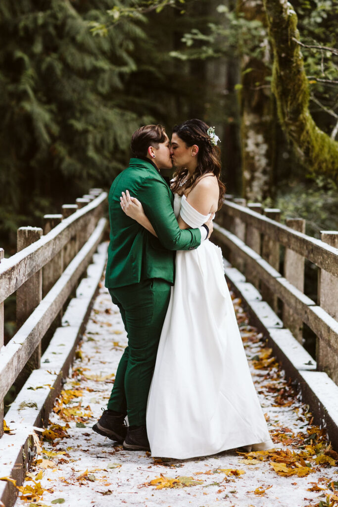 brides kiss on bridge in middle of forest