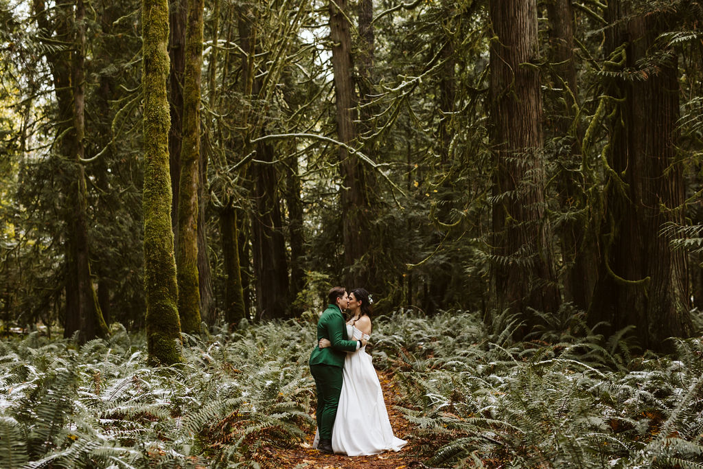 two brides embrace in the middle of a forest elopement