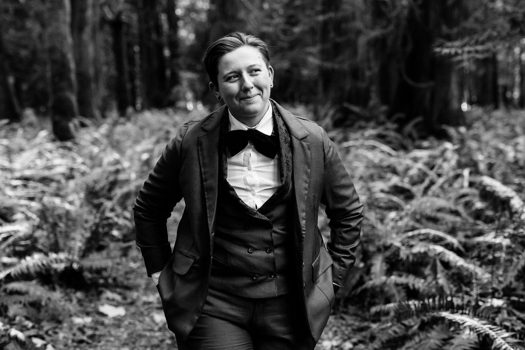bride in suit poses in forest elopement
