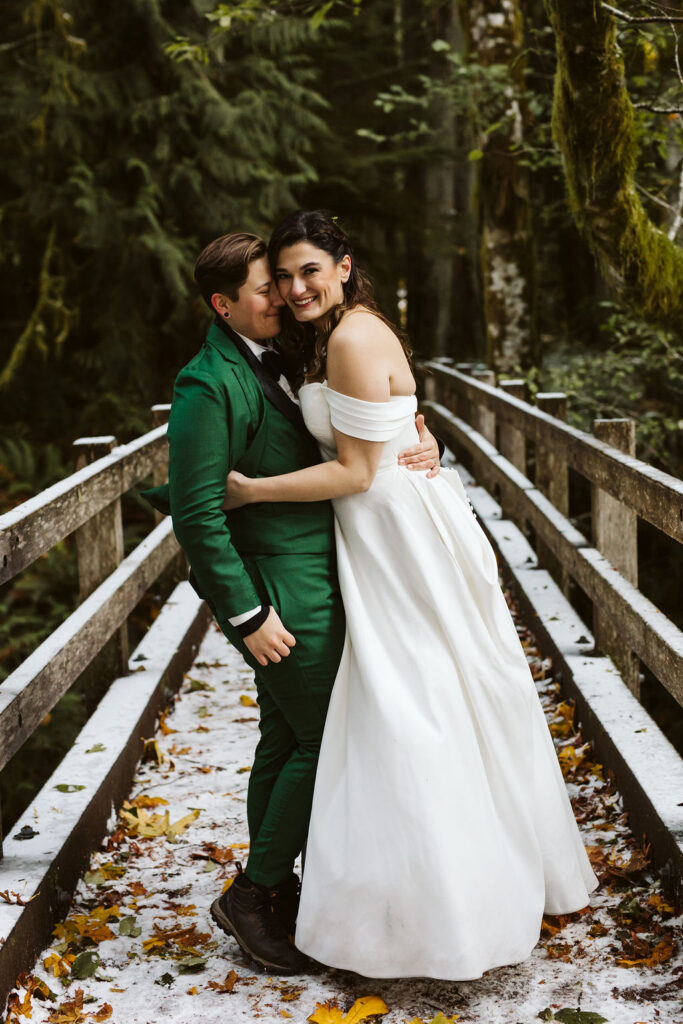 two brides pose on bridge in forest during olympic national park elopement