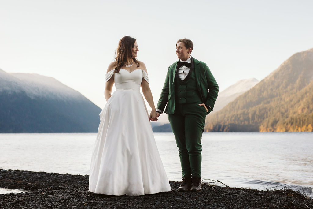 two brides stand on shore of lake crescent during elopement