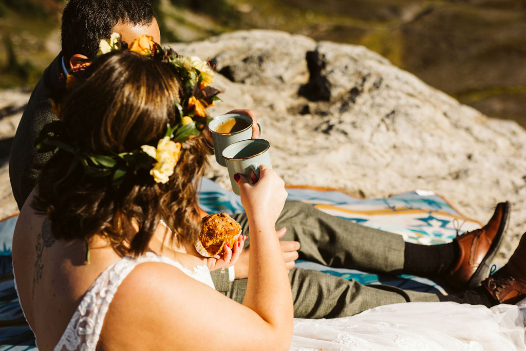 bride and groom share coffee on edge of cliff during north cascades elopement