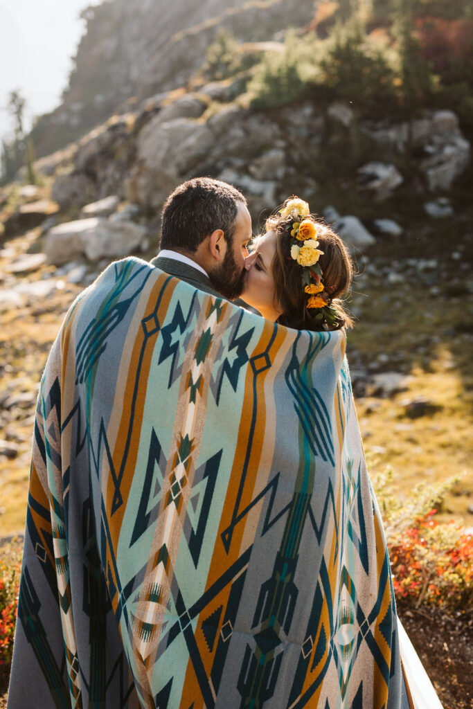 bride and groom cuddle inside blanket
