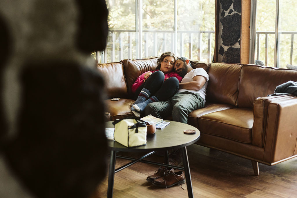 man and woman cuddle on couch 