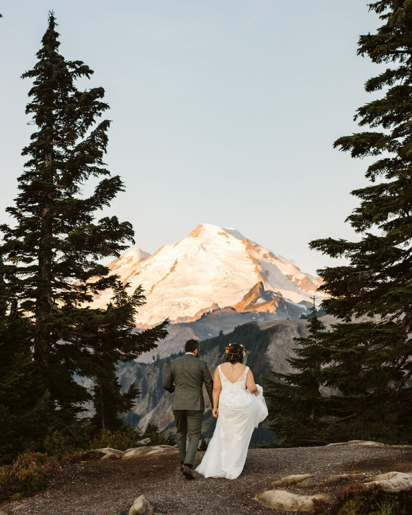 bride and groom walk on path with mt baker in the background